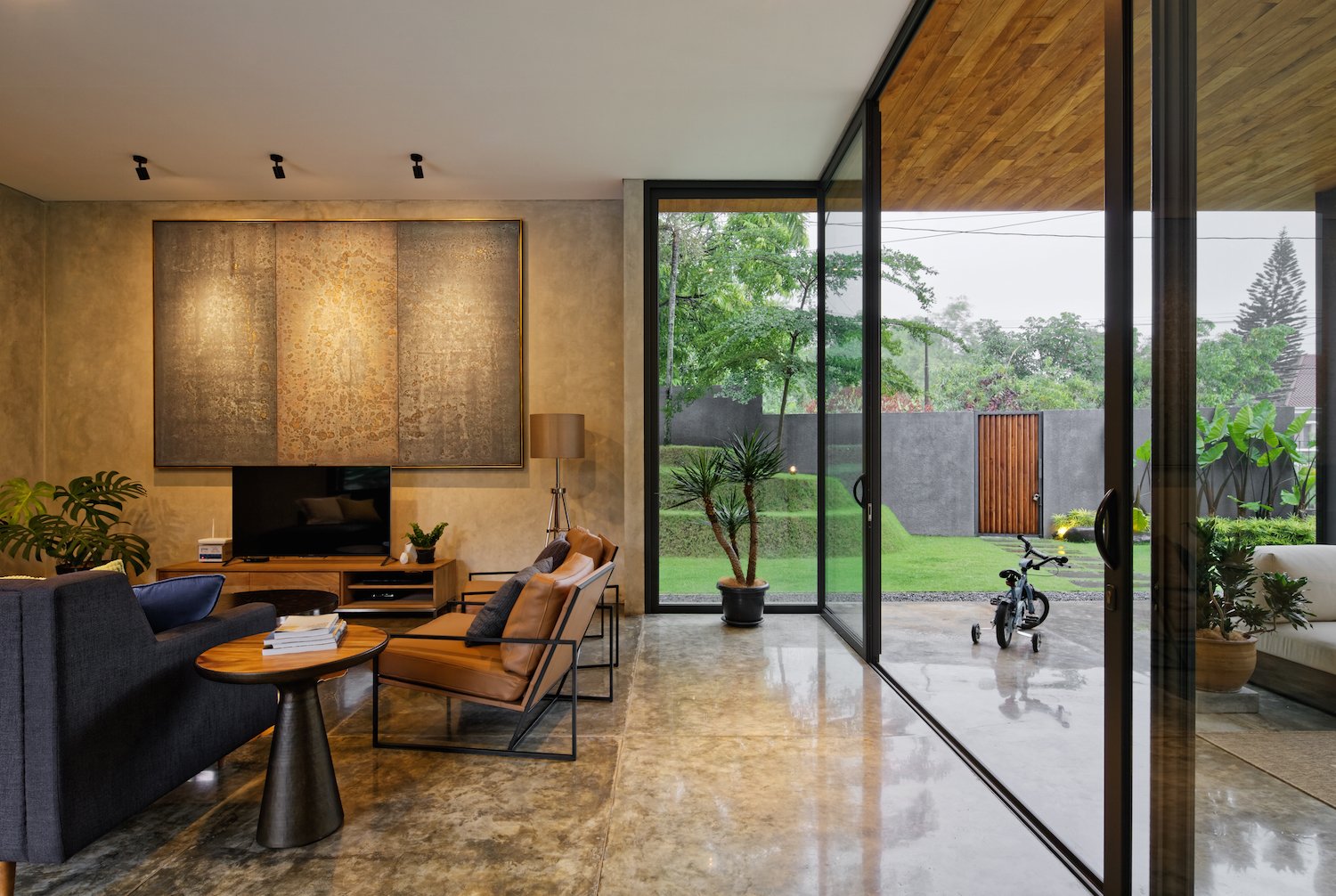 Raw concrete walls and polished concrete floors are used in the interior to form a neutral backdrop for built-in wood furniture and colorful rugs and artworks.