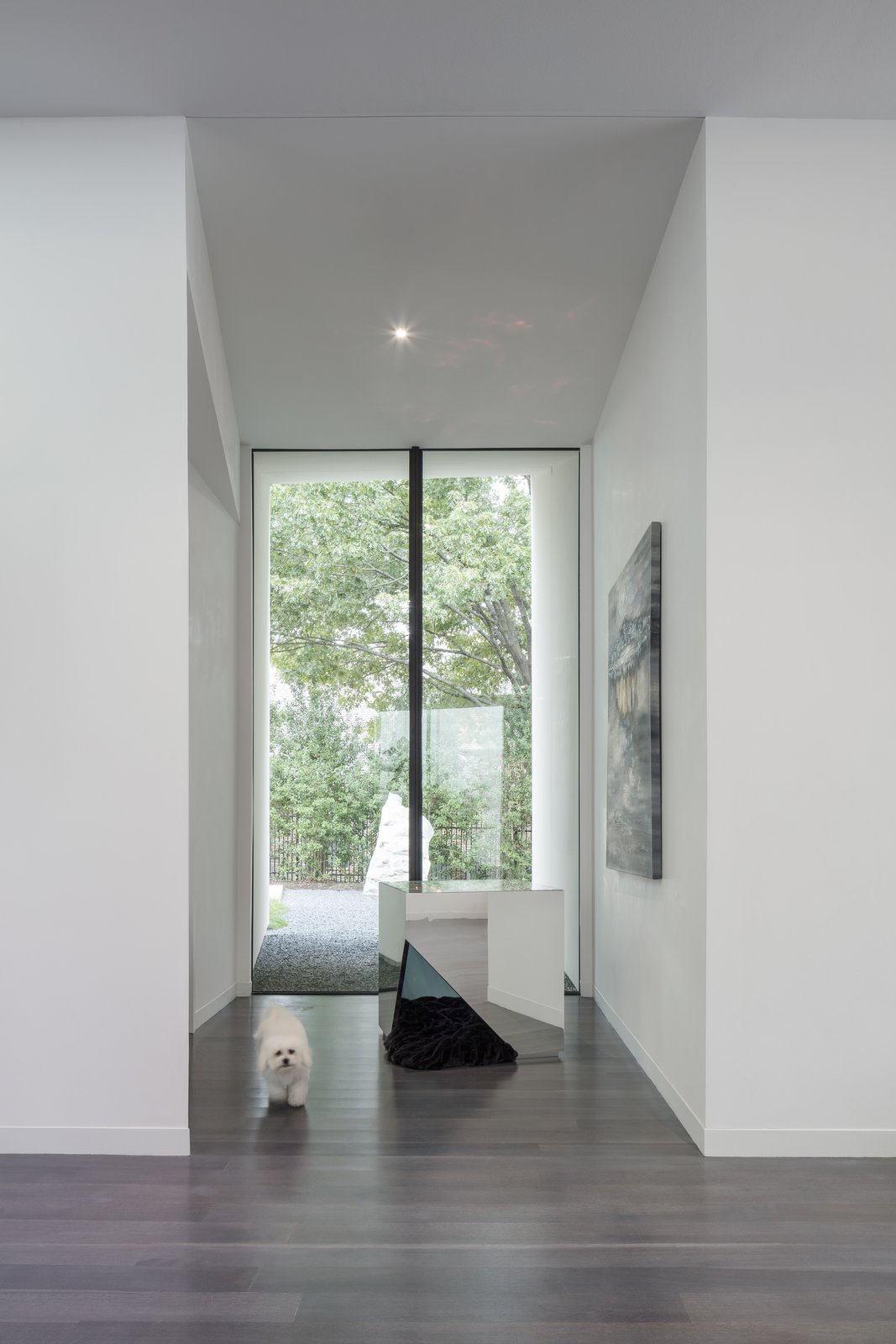 Looking north from the front door, one looks through a 12'h x 8' w window looking on the stone embedded in the landscape which came from the excavated bedrock when construction the home.