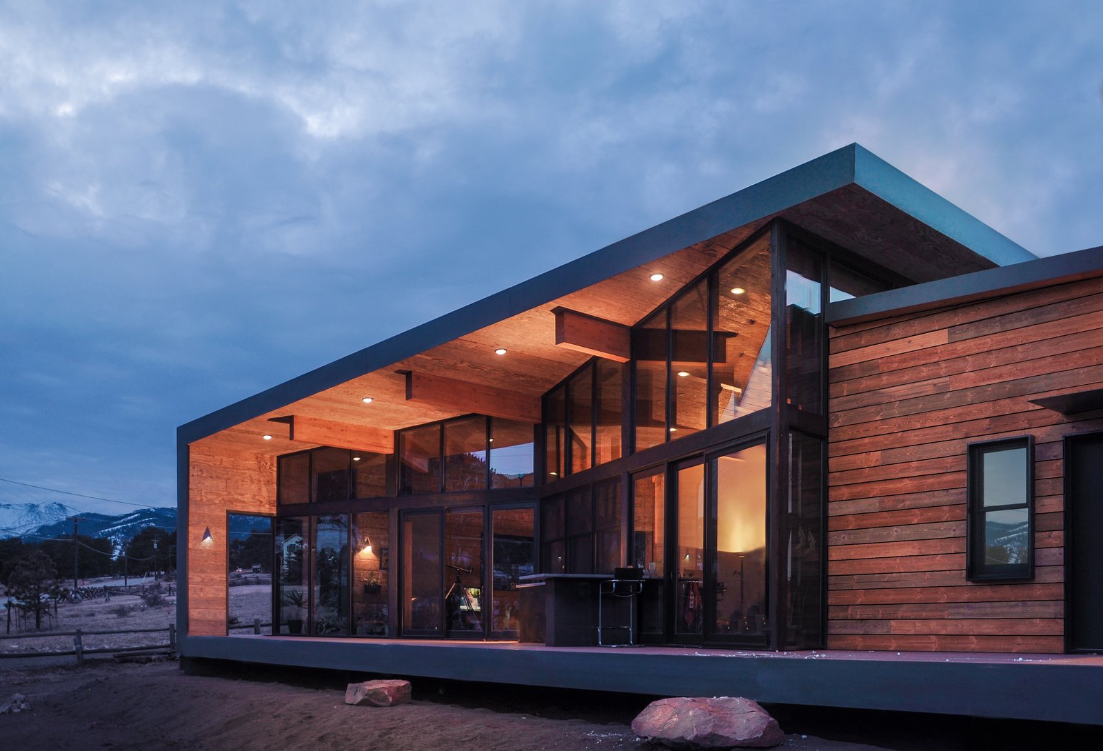 A large window wall folds in to create a spacious deck that wraps up and over to become the roof and overhang of the home.