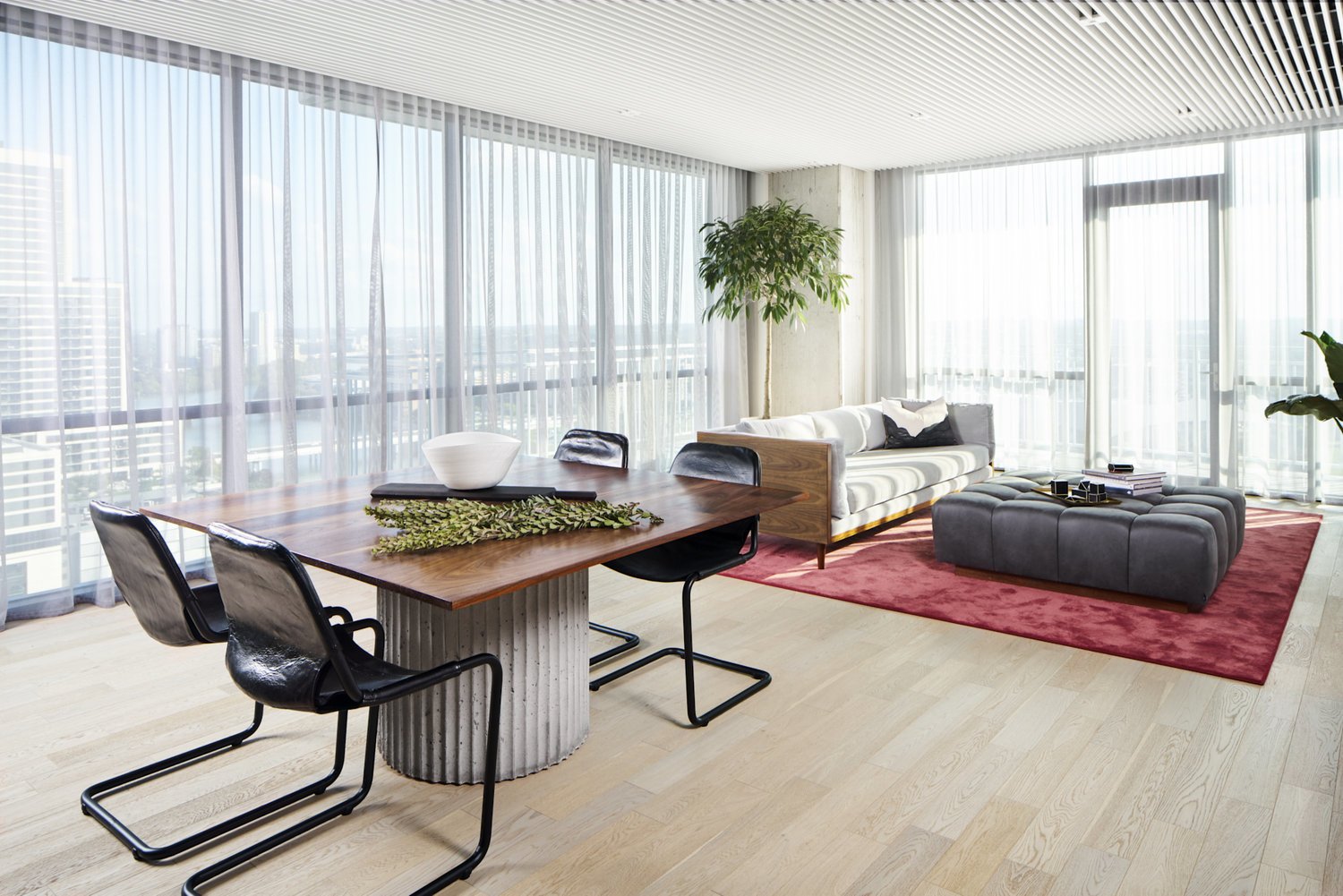 Modern living room with leather sling chair, walnut frame sofa, and wooden tabletop with a concrete base.