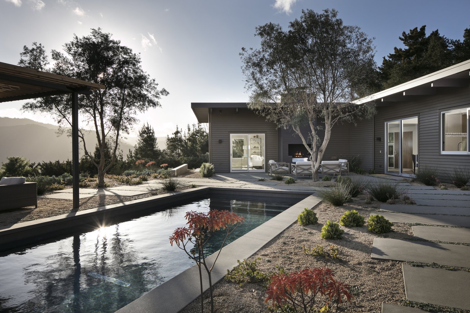 Backyard and outdoor living spaces, looking over the pool to the home and mountain views